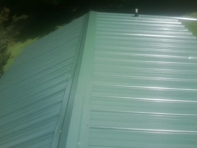 New green metal panels meeting at the ridge of a roof — Flat Roof Repair work by our crew in Estes Park