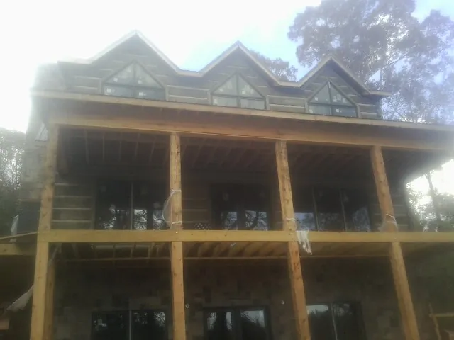 Dormers and porch framing on a large log home under construction — Roof Coating work by our crew in Estes Park