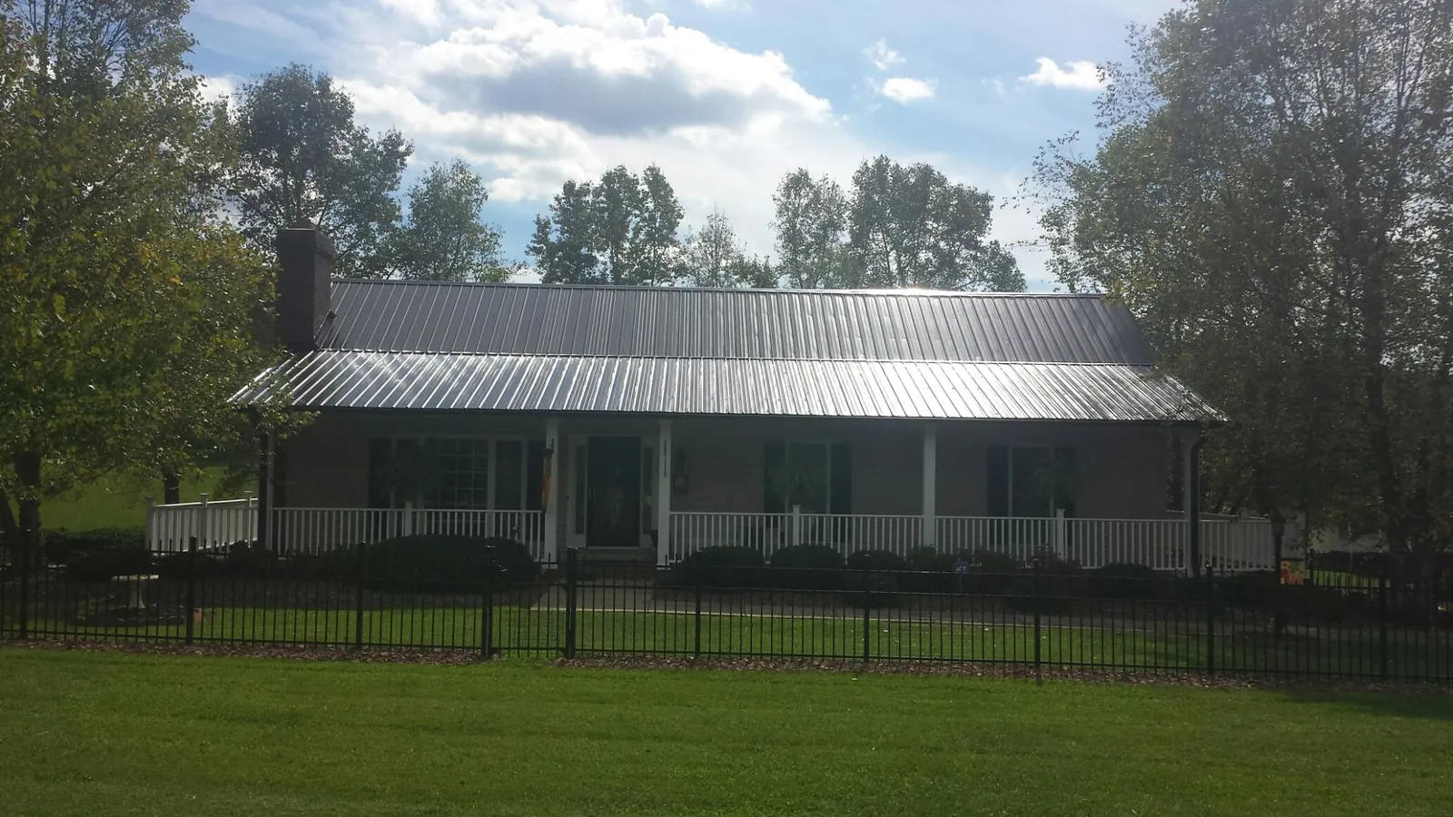 Gray metal roof on a brick ranch with a full width front porch — Gutter Guard Installation work by our crew in Estes Park