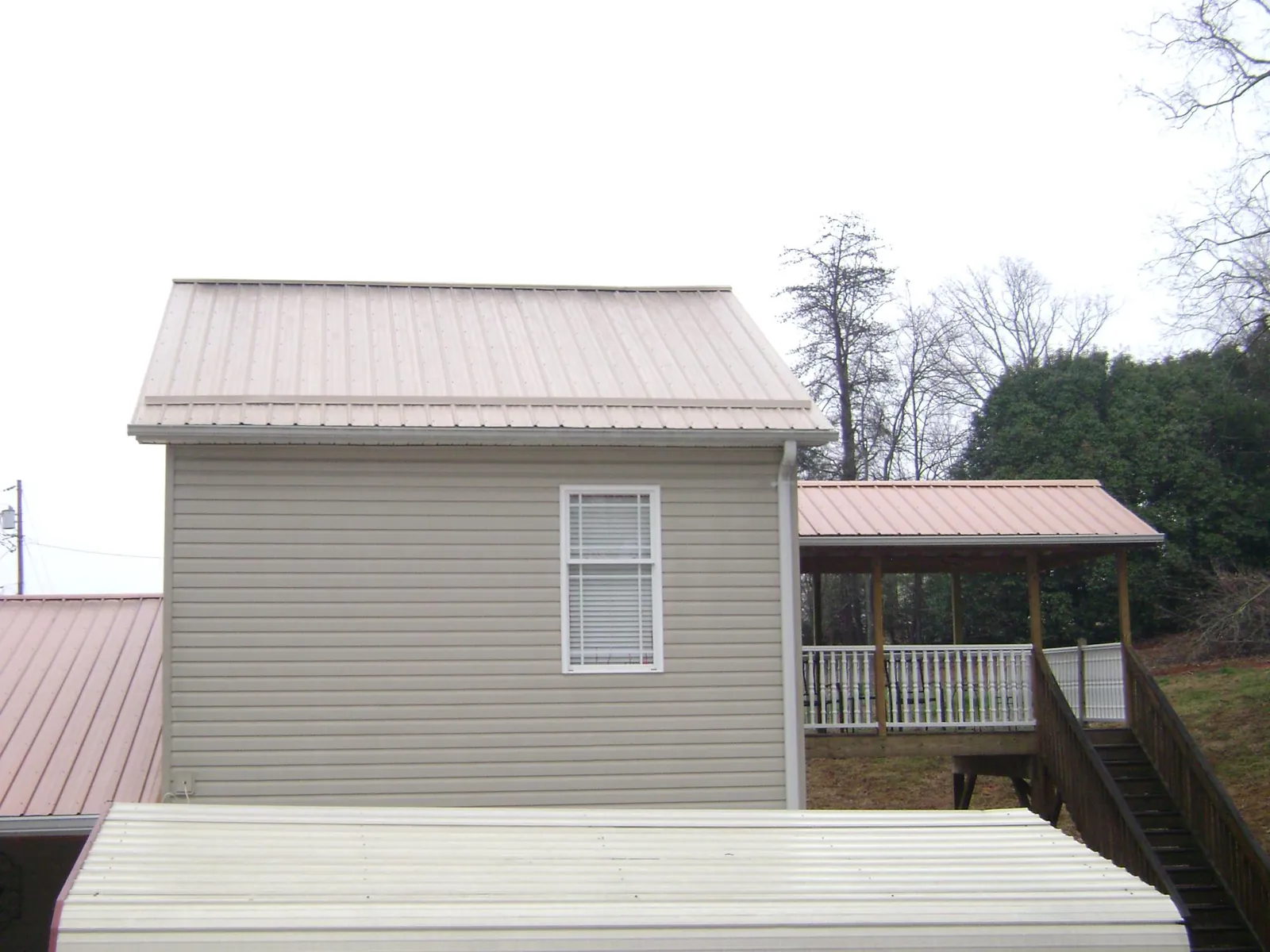 Tan metal roofs on a two story addition and attached porch, from a Roof Replacement job in Estes Park