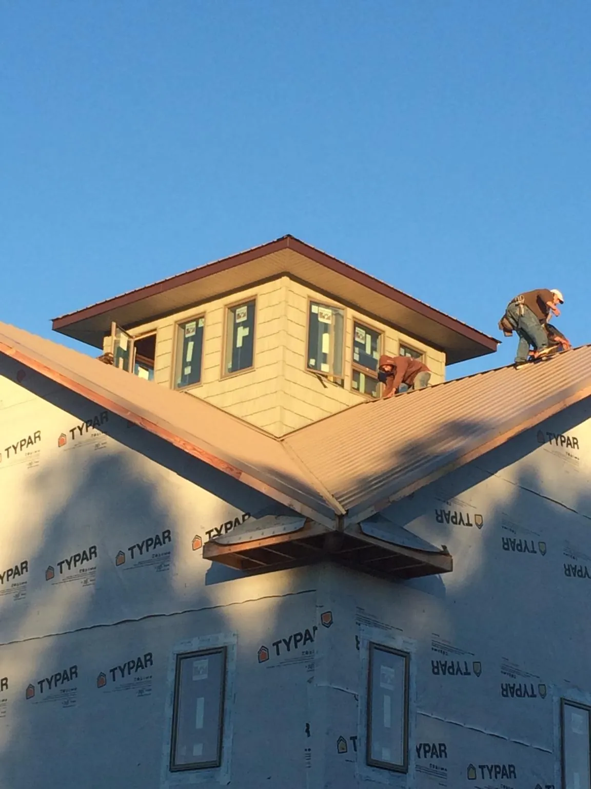 Roofers working around a rooftop cupola on a new metal roof at sunset — Roof Waterproofing in Estes Park by Roofing Brothers